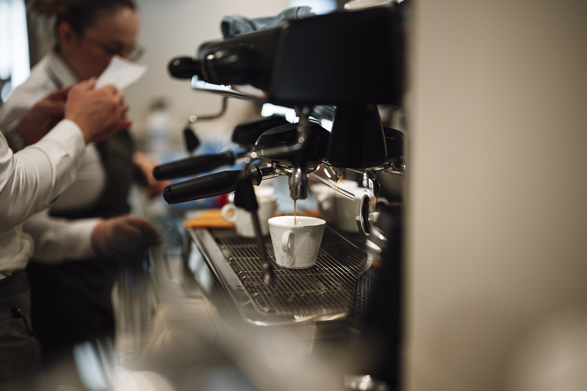 Barista pulling espresso at a busy café